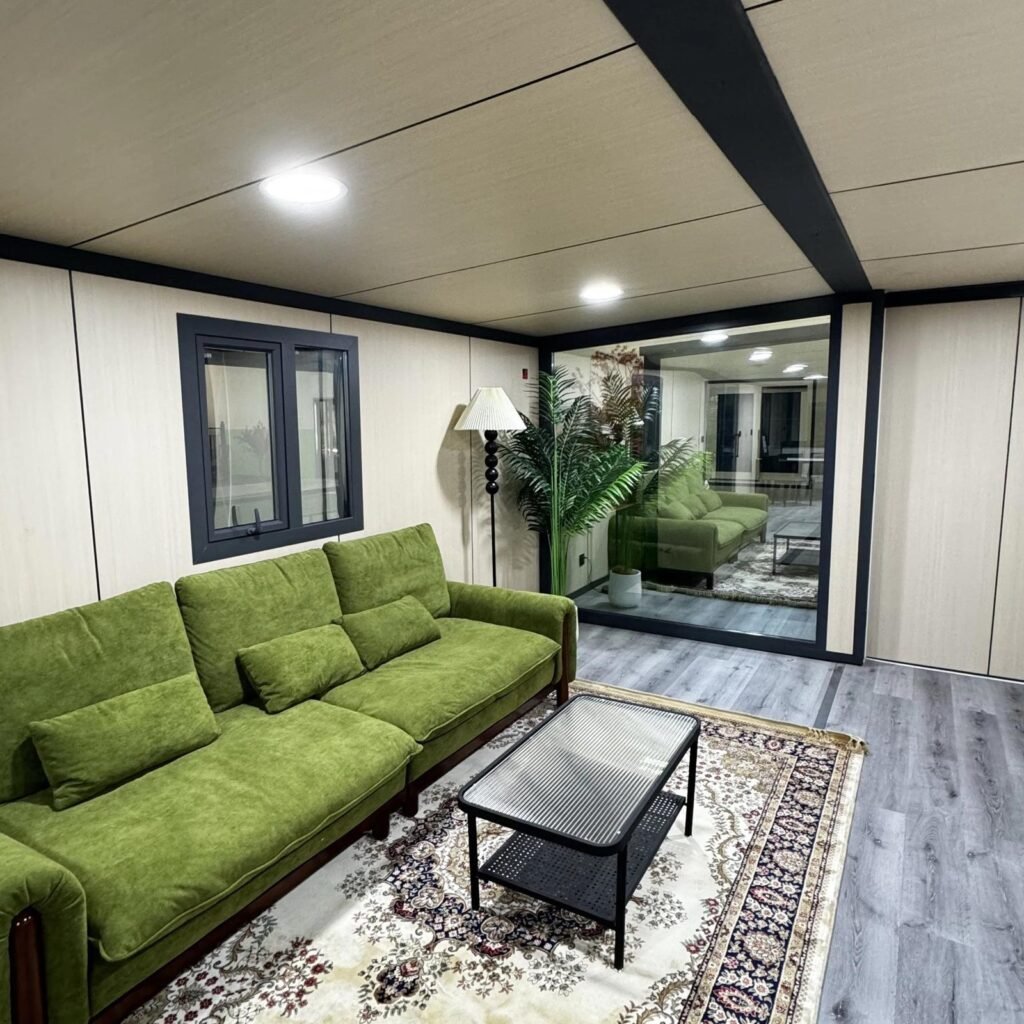 Luxury modular home lounge interior with green sofa and oversized window – MOB TIMBERCREST by Prefabia